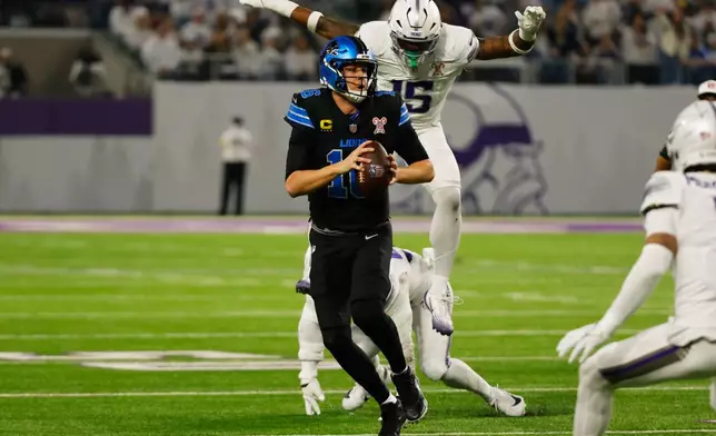 Detroit Lions quarterback Jared Goff, left, is chased by Minnesota Vikings linebacker Dallas Turner during the first half of an NFL football game, Thursday, Dec. 25, 2025, in Minneapolis. (AP Photo/Bruce Kluckhohn)