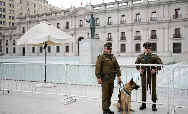 Police stand in front of La Moneda palace ahead of the presidential runoff election in Santiago, Chile, Thursday, Dec. 11, 2025. (AP Photo/Natacha Pisarenko)