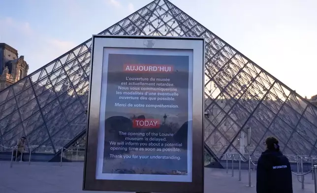 A board advises opening delays outside the pyramid of the Louvre museum as workers at the Louvre will vote to go on strike or continue talks with the government after months of mounting pressure on the world's most visited museum, Monday, Dec. 15, 2025 in Paris. (AP Photo/Michel Euler)