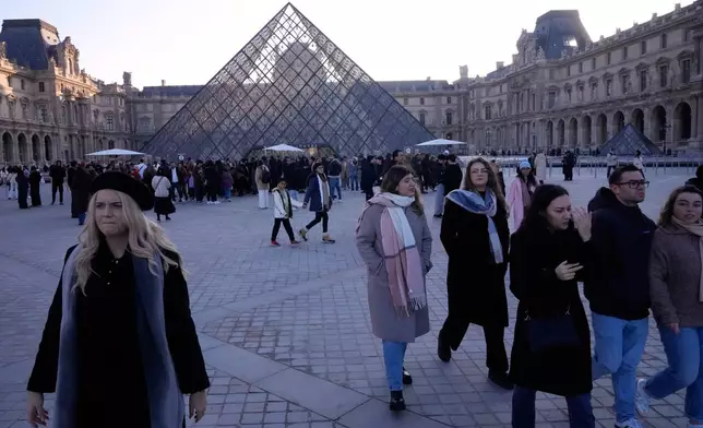 Visitors leave the Louvre museum shortly before workers at the Louvre voted to strike for the day over working conditions and other complaints, Monday, Dec. 15, 2025 in Paris. (AP Photo/Michel Euler)