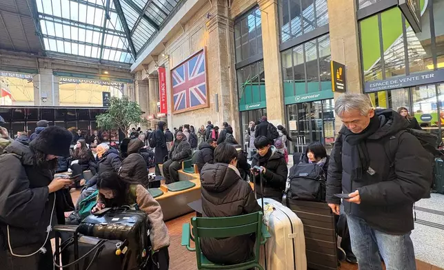 Travelers wait at the Gare du Nord station after an incident related to the power supply to trains occurred last night in part of the Channel Tunnel, affecting train and shuttle traffic. Tuesday, Dec. 30, 2025 in Paris. (AP Photo/Christophe Ena)
