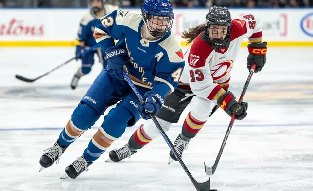 Vancouver Goldeneyes' Claire Thompson (42) and Ottawa Charge's Sarah Wozniewicz (23) vie for the puck during the third period of a PWHL hockey game in Vancouver, British Columbia, Tuesday, Dec. 16, 2025. (Ethan Cairns/The Canadian Press via AP)
