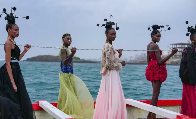 FILE - Models wear creations on a traditional fishing boat during Dakar Fashion Week in Senegal, Saturday, Dec. 6, 2025. (AP Photo/Misper Apawu, File)