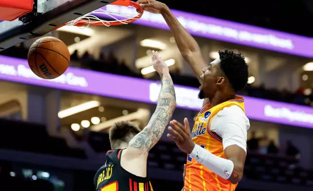 Charlotte Hornets forward Brandon Miller, right, dunks over Atlanta Hawks guard Vit Krejci during the first half of an NBA basketball game in Charlotte, N.C., Thursday, Dec. 18, 2025. (AP Photo/Nell Redmond)