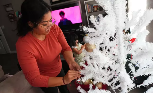 Cristina Osornio and her 3-year-old daughter, Valentina, decorate a Christmas tree in their apartment, Nov. 18, 2025, in Rogers, Ark. (AP Photo/Julio Cortez)