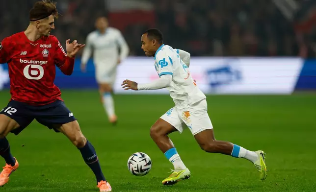 Lille's Thomas Meunier, left, and Marseille's Igor Paixao challenge for the ball during the French League One soccer match between Lille and Marseille in Villeneuve-d'Ascq, outside Lille, France, Friday, Dec. 5, 2025. (AP Photo/Jean-Francois Badias)