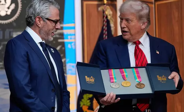 FILE - President Donald Trump listens as Casey Wasserman, chairman of LA28, presents him a full set of medals from the 1984 Olympics in Los Angeles, during an event regarding the 2028 Los Angeles Olympic Games, in the South Court Auditorium of the Eisenhower Executive Office Building on the White House campus, Tuesday, Aug. 5, 2025, in Washington. (AP Photo/Julia Demaree Nikhinson, File)