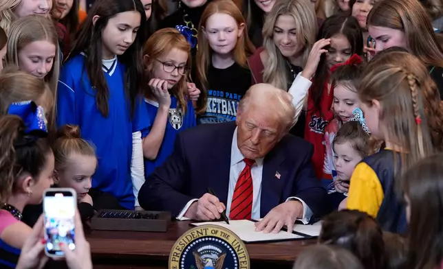 FILE - President Donald Trump signs an executive order at the White House in Washington, Feb. 5, 2025, barring transgender female athletes from competing in women's or girls' sporting events. (AP Photo/Alex Brandon, File)