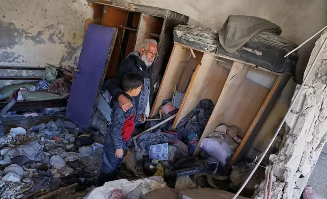Qassim Hamadeh, who lost two sons, a daughter-in-law, and his 4- and 10-year-old grandsons, among 13 villagers killed when Israeli troops raided Beit Jin, southwestern Syria, on Nov. 2, looks at the damage from the raid alongside one surviving grandson, Dec. 1, 2025. (AP Photo/Omar Albam)