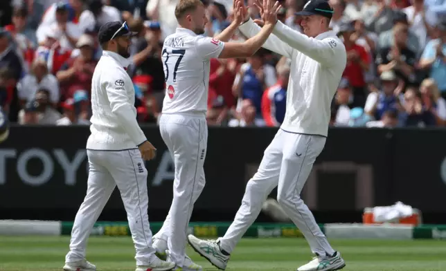 England's Gus Atkinson, center, celebrates with teammates after bowling Australia's Travis Head during their Ashes cricket test match in Melbourne, Friday, Dec. 26, 2025. (AP Photo/Hamish Blair)