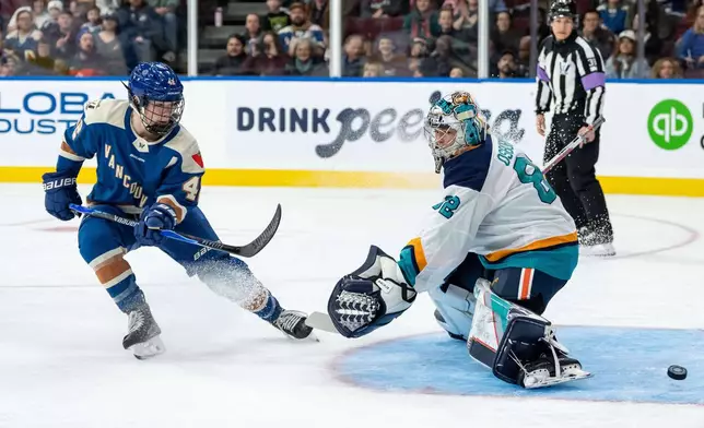 Vancouver Goldeneyes' Claire Thompson, left, watches as the puck gets by New York Sirens goaltender Kayle Osborne (82) during the first period of a PWHL hockey game in Vancouver, British Columbia, Saturday, Dec. 6, 2025. (Ethan Cairns/The Canadian Press via AP)