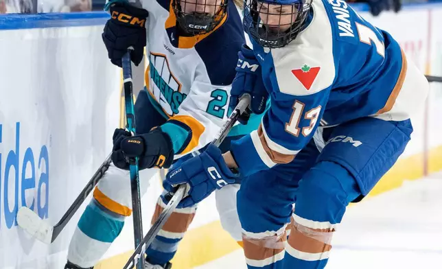New York Sirens' Casey O'Brien (26) and Vancouver Goldeneyes' Tereza Vanisova (13) vie for the puck as Goldeneyes' Mellissa Channell-Watkins (23) watches during the second period of a PWHL hockey game in Vancouver, British Columbia, Saturday, Dec. 6, 2025. (Ethan Cairns/The Canadian Press via AP)
