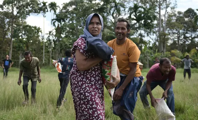 Flood survivors react as they receive relief goods during an aerial aid distribution using national disaster mitigation agency's helicopter in North Aceh, Indonesia, Thursday, Dec. 4, 2025. (AP Photo/Reza Saifullah)