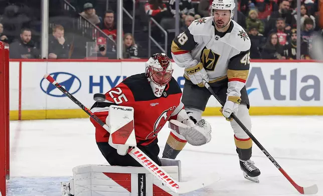 New Jersey Devils goaltender Jacob Markstrom and Vegas Golden Knights center Tomas Hertl (48) watch a shot go wide of the net during the first period of an NHL hockey game Friday, Dec. 5, 2025, in Newark, N.J. (AP Photo/Adam Hunger)