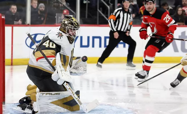 Vegas Golden Knights goaltender Akira Schmid, left, makes a save during the second period of an NHL hockey game against the New Jersey Devils, Friday, Dec. 5, 2025, in Newark, N.J. (AP Photo/Adam Hunger)