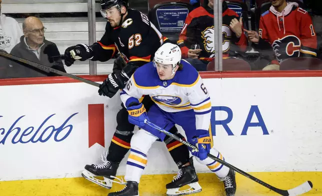 Buffalo Sabres' Zach Benson, right, checks Calgary Flames' MacKenzie Weegar during the first period of an NHL hockey game in Calgary, Alberta, Monday, Dec. 8, 2025. (Jeff McIntosh/The Canadian Press via AP)