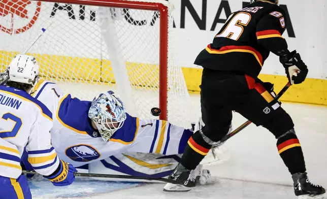Buffalo Sabres' goalie Ukko-Pekka Luukkonen, left, makes a save on a shot from Calgary Flames' Joel Farabee during the second period of an NHL hockey game, in Calgary, Alberta, Monday, Dec. 8, 2025. (eff McIntosh/The Canadian Press via AP)