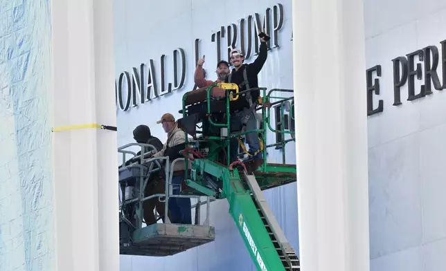 Workers install Donald J. Trump above the current signage on the Kennedy Center on Friday, Dec. 19, 2025, in Washington. (AP Photo/Jacquelyn Martin)
