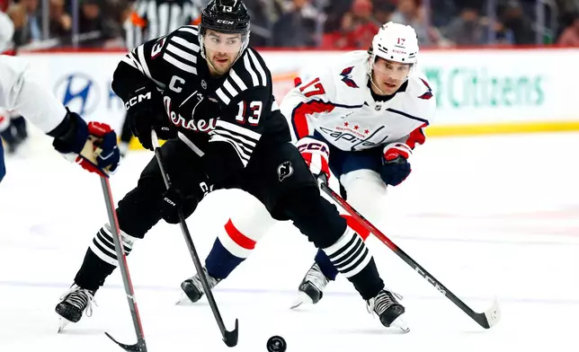 New Jersey Devils center Nico Hischier (13) skates with the puck against Washington Capitals center Dylan Strome (17) during the second period of an NHL hockey game Saturday, Dec. 27, 2025, in Newark, N.J. (AP Photo/Noah K. Murray)