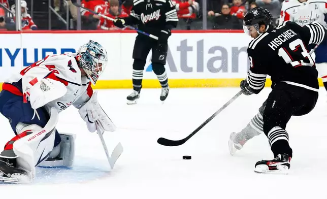 Washington Capitals goaltender Logan Thompson (48) defends against New Jersey Devils center Nico Hischier (13) during the second period of an NHL hockey game Saturday, Dec. 27, 2025, in Newark, N.J. (AP Photo/Noah K. Murray)