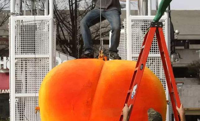 FILE - Entertainment Design Group project manager Gary Seputis stands on the giant peach as he positions himself before he attaches two leaves in preparation for the 2012 Peach Drop at Underground Atlanta Friday, Dec 30, 2011, in Atlanta. ( Jason Getz/Atlanta Journal-Constitution via AP)