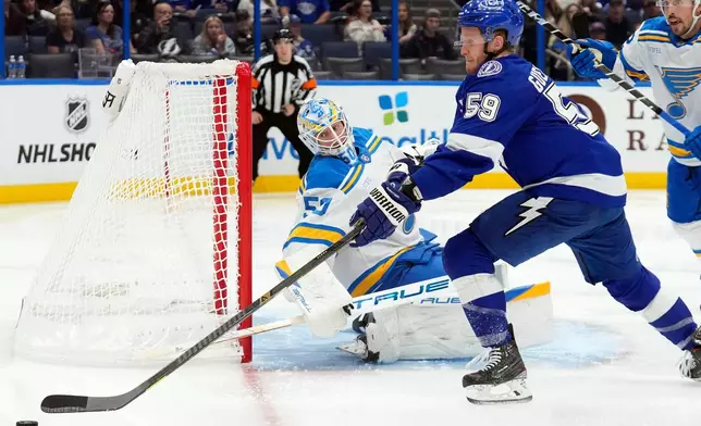 St. Louis Blues goaltender Jordan Binnington (50) makes a save on a shot by Tampa Bay Lightning center Jake Guentzel (59) during the second period of an NHL hockey game Monday, Dec. 22, 2025, in Tampa, Fla. (AP Photo/Chris O'Meara)