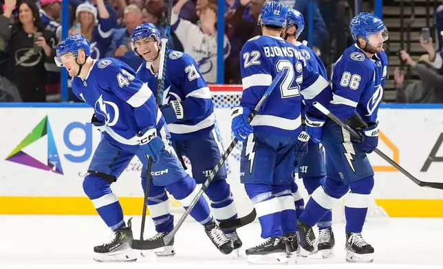Tampa Bay Lightning defenseman Darren Raddysh (43) celebrates his goal against the St. Louis Blues with teammates, including center Brayden Point (21), right wing Oliver Bjorkstrand (22) and right wing Nikita Kucherov (86) during the first period of an NHL hockey game Monday, Dec. 22, 2025, in Tampa, Fla. (AP Photo/Chris O'Meara)