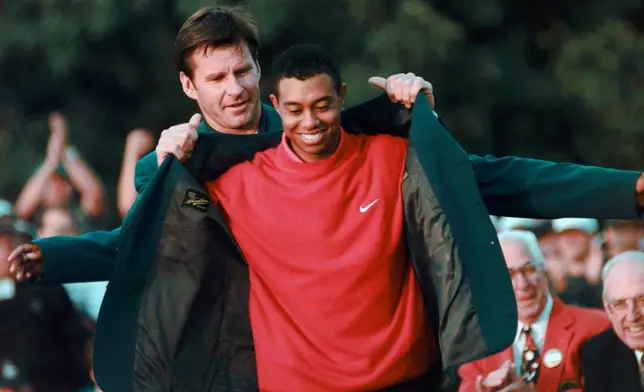 FILE - Masters champion Tiger Woods receives his Green Jacket from last year's winner Nick Faldo, left, at the Augusta National Golf Club, April 13, 1997, in Augusta, Ga. (AP Photo/ Dave Martin, File)
