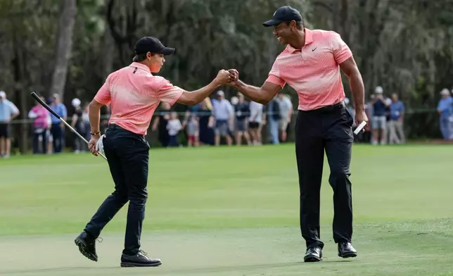 FILE - Tiger Woods, right and his son Charlie Woods bump fists on the ninth green during the first round of the PNC Championship golf tournament, Saturday, Dec. 17, 2022, in Orlando, Fla. (AP Photo/Kevin Kolczynski, File)