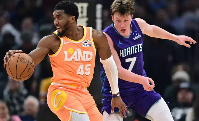 Cleveland Cavaliers guard Donovan Mitchell (45) spins around Charlotte Hornets guard Kon Knueppel (7) in the first half of an NBA basketball game, Monday, Dec. 22, 2025, in Cleveland. (AP Photo/David Dermer)