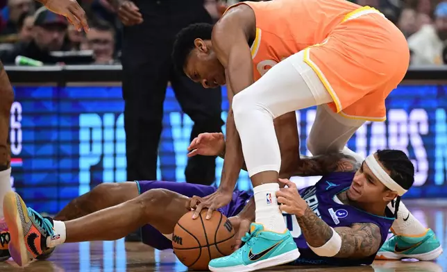 Cleveland Cavaliers forward De'Andre Hunter and Charlotte Hornets guard Tre Mann wrestle for a loose ball in the first half of an NBA basketball game, Monday, Dec. 22, 2025, in Cleveland. (AP Photo/David Dermer)