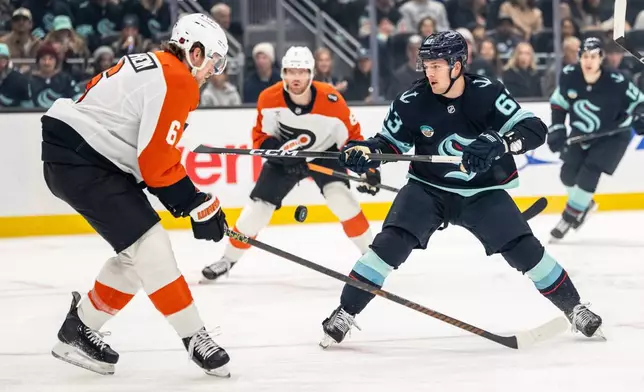 Seattle Kraken forward Jacob Melanson, front right, battles Philadelphia Flyers defenseman Travis Sanheim, left, for the puck during the first period of an NHL hockey game Sunday, Dec. 28, 2025, in Seattle. (AP Photo/Stephen Brashear)