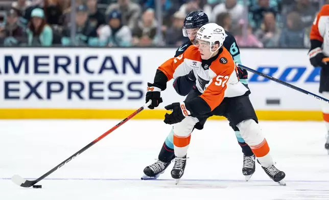 Philadelphia Flyers forward Denver Barkey (52) and Seattle Kraken forward Frederick Gaudreau battle for the puck during the second period of an NHL hockey game, Sunday, Dec. 28, 2025, in Seattle. (AP Photo/Stephen Brashear)