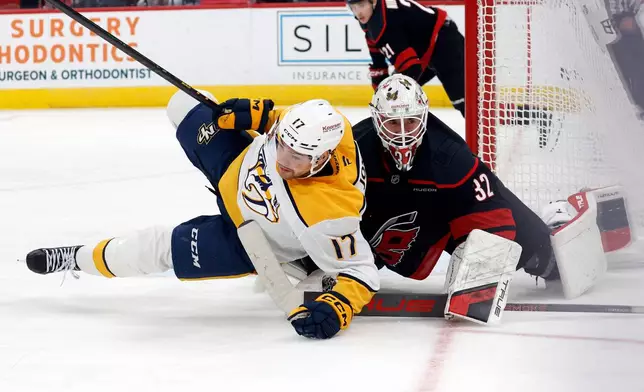 Nashville Predators' Tyson Jost (17) collides with Carolina Hurricanes goaltender Brandon Bussi (32) during the first period of an NHL hockey game in Raleigh, N.C., Saturday, Dec. 6, 2025. (AP Photo/Karl DeBlaker)