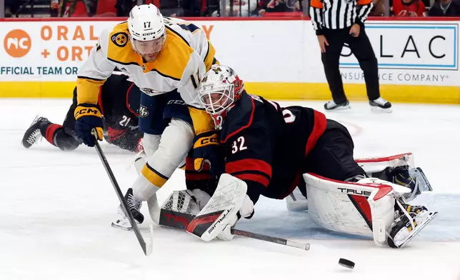Nashville Predators' Tyson Jost (17) collides with Carolina Hurricanes goaltender Brandon Bussi (32) during the first period of an NHL hockey game in Raleigh, N.C., Saturday, Dec. 6, 2025. (AP Photo/Karl DeBlaker)