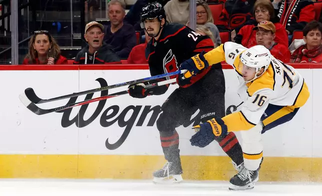 Carolina Hurricanes' Seth Jarvis (24) battles with Nashville Predators' Brady Skjei (76) during the second period of an NHL hockey game in Raleigh, N.C., Saturday, Dec. 6, 2025. (AP Photo/Karl DeBlaker)