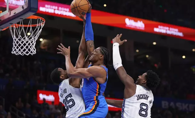 Oklahoma City Thunder guard Jalen Williams, center, goes up to dunk against Memphis Grizzlies center Christian Koloko (35) and forward Jaren Jackson Jr. (8)during the second half of an NBA basketball game Monday, Dec. 22, 2025, in Oklahoma City. (AP Photo/Nate Billings)