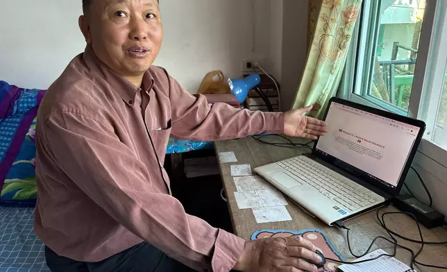 Lu Taizhi, a Chinese Christian who is waiting to be resettled in the United States, points to the webpage of the International Rescue Committee, which is under maintenance and not operational in Ban Wawee village, Chiang Rai Province, Thailand, Nov. 27, 2025. (AP Photo/ Tian Macleod Ji)