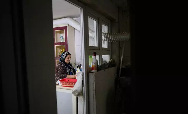 Syrian refugee Hayat Fatah, 65, cleans dishes at her home in Irbil, Iraq, Nov. 16, 2025. (AP Photo/Farid Abdulwahed)