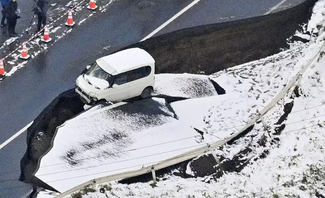 This aerial photo shows a vehicle sitting on a damaged road in Tohoku town, Aomori prefecture, northern Japan Tuesday, Dec. 9, 2025, following a powerful earthquake on late Monday. (Kyodo News via AP)