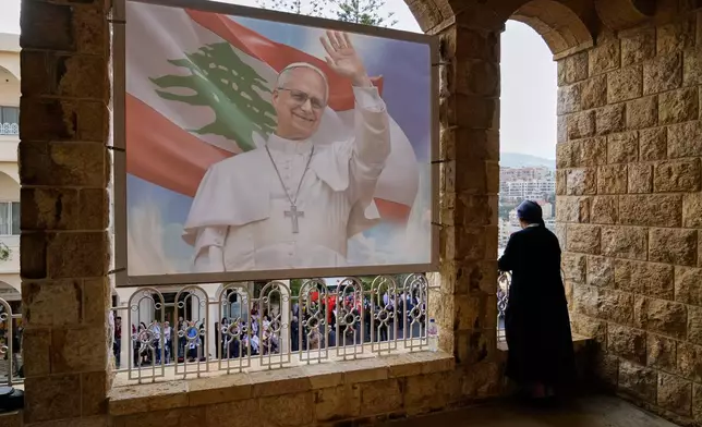 A nun looks from a balcony as people wait for the arrival of Pope Leo XIV at the De la Croix hospital in Jal el Dib, Lebanon, Tuesday, Dec. 2, 2025. (AP Photo/Hassan Ammar)