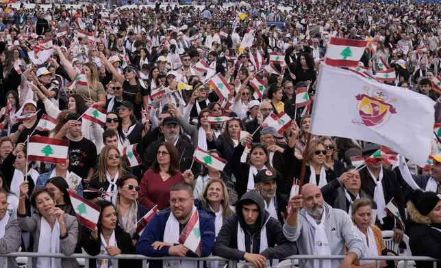 Worshippers wave Lebanese and Vatican flags as they wait for Pope Leo XIV to celebrate a Holy Mass at Beirut waterfront, in Beirut, Lebanon, Tuesday, Dec. 2, 2025. (AP Photo/Bilal Hussein)