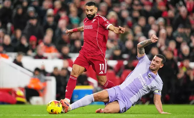 Liverpool's Mohamed Salah, left, challenges for the ball with Brighton's Lewis Dunk during the English Premier League soccer match between Liverpool and Brighton and Hove Albion in Liverpool, England, Saturday, Dec. 13, 2025. (AP Photo/Jon Super)