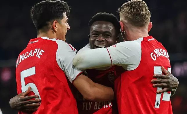 Arsenal's Bukayo Saka, center, celebrates with teammates after his team scored the opening goal during the English Premier League soccer match between Arsenal and Wolves in London, Sunday, Dec. 14, 2025. (AP Photo/Richard Pelham)