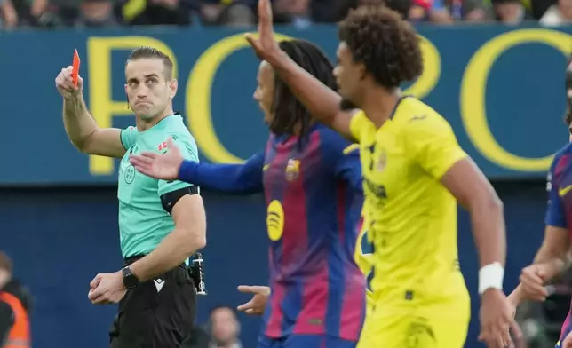The referee shows a red card to Villarreal's Renato Veiga, right, during the Spanish La Liga soccer match between Villarreal and Barcelona in Villarreal, Spain, Sunday, Dec. 21, 2025. (AP Photo/Alberto Saiz)