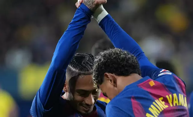 Barcelona's Lamine Yamal, right, celebrates with his teammate Barcelona's Raphinha after scoring his side's second goal during the Spanish La Liga soccer match between Villarreal and Barcelona in Villarreal, Spain, Sunday, Dec. 21, 2025. (AP Photo/Alberto Saiz)