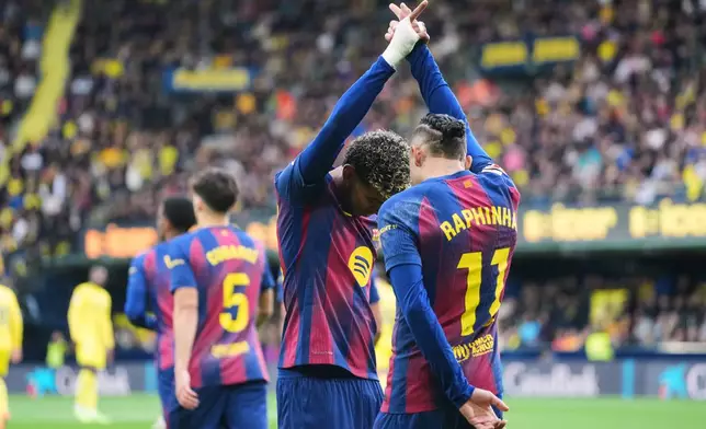 Barcelona's Raphinha, back, celebrates with his teammate Barcelona's Lamine Yamal after scoring the opening goal from a penalty kick during the Spanish La Liga soccer match between Villarreal and Barcelona in Villarreal, Spain, Sunday, Dec. 21, 2025. (AP Photo/Alberto Saiz)