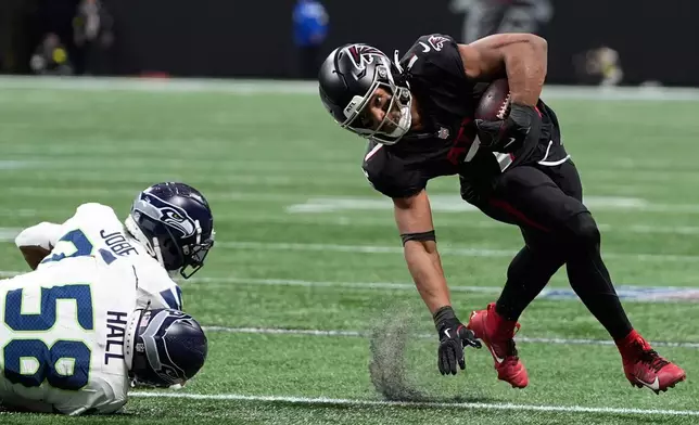 Atlanta Falcons running back Bijan Robinson (7) avoids tackles from Seattle Seahawks linebacker Derick Hall (58) and cornerback Josh Jobe (29) during the first half of an NFL football game, Sunday, Dec. 7, 2025, in Atlanta. (AP Photo/Brynn Anderson)