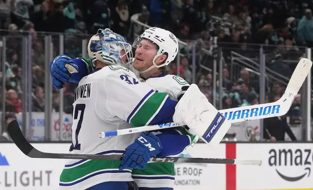 Vancouver Canucks right wing Brock Boeser, facing, celebrates a win in a shootout against the Seattle Kraken with goaltender Kevin Lankinen, left, after an NHL hockey game Monday, Dec. 29, 2025, in Seattle. (AP Photo/Lindsey Wasson)