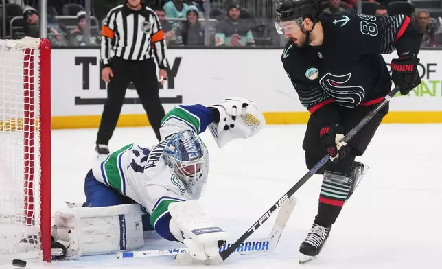 Seattle Kraken center Frederick Gaudreau has his shot blocked by Vancouver Canucks goaltender Kevin Lankinen, left, during a shootout in an NHL hockey game Monday, Dec. 29, 2025, in Seattle. (AP Photo/Lindsey Wasson)